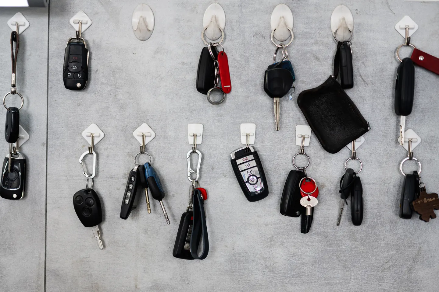 Car keys and fobs hanging on hooks on a workshop wall